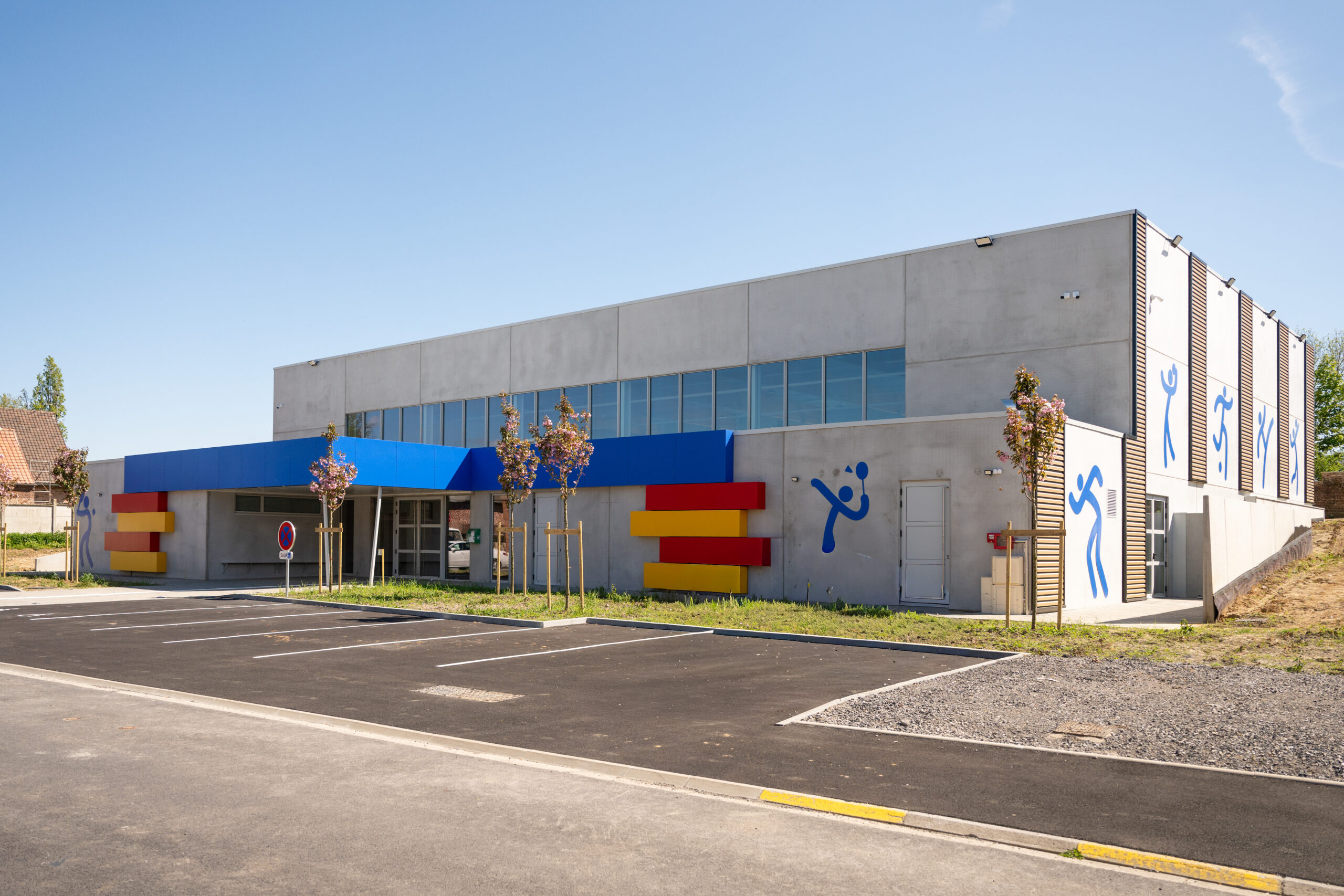 Industriebouw van prefab betonnen sporthal met kleurrijke accenten en sportpictogrammen