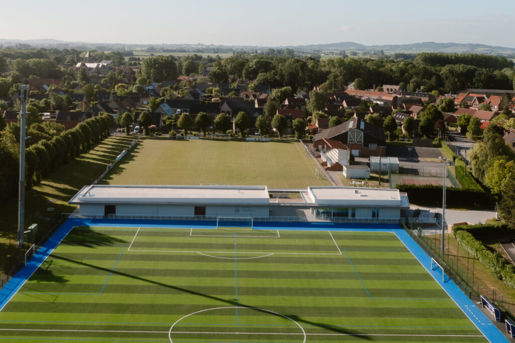 A modern sports complex with synthetic and natural grass soccer fields surrounded by residential houses