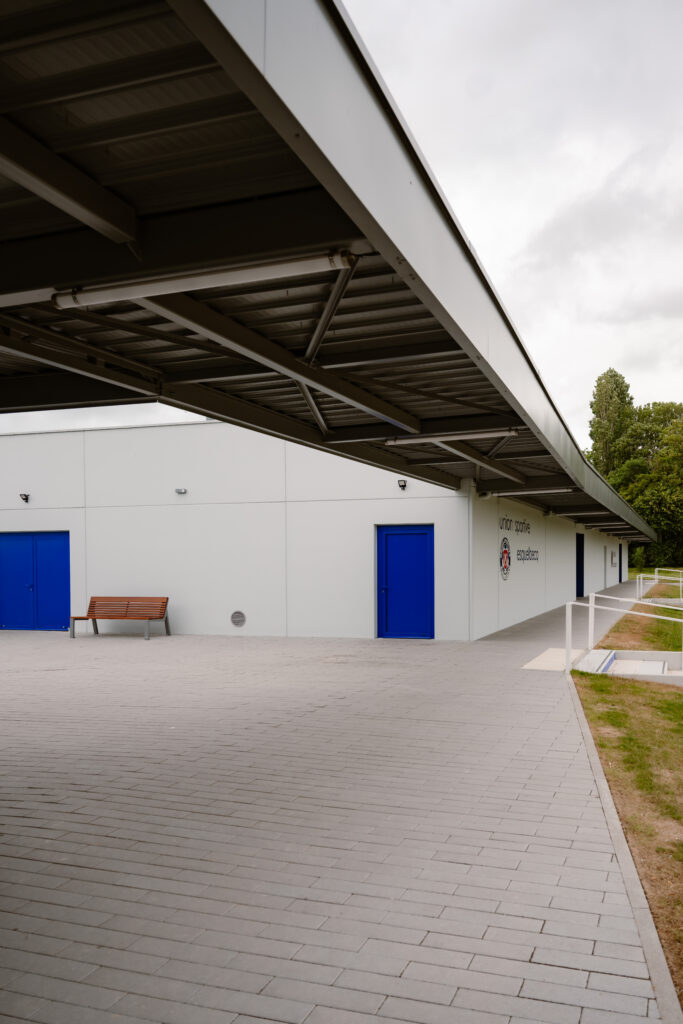 Moderne industriële loods met blauw geschilderde deuren en overdekte betonnen buitenruimte