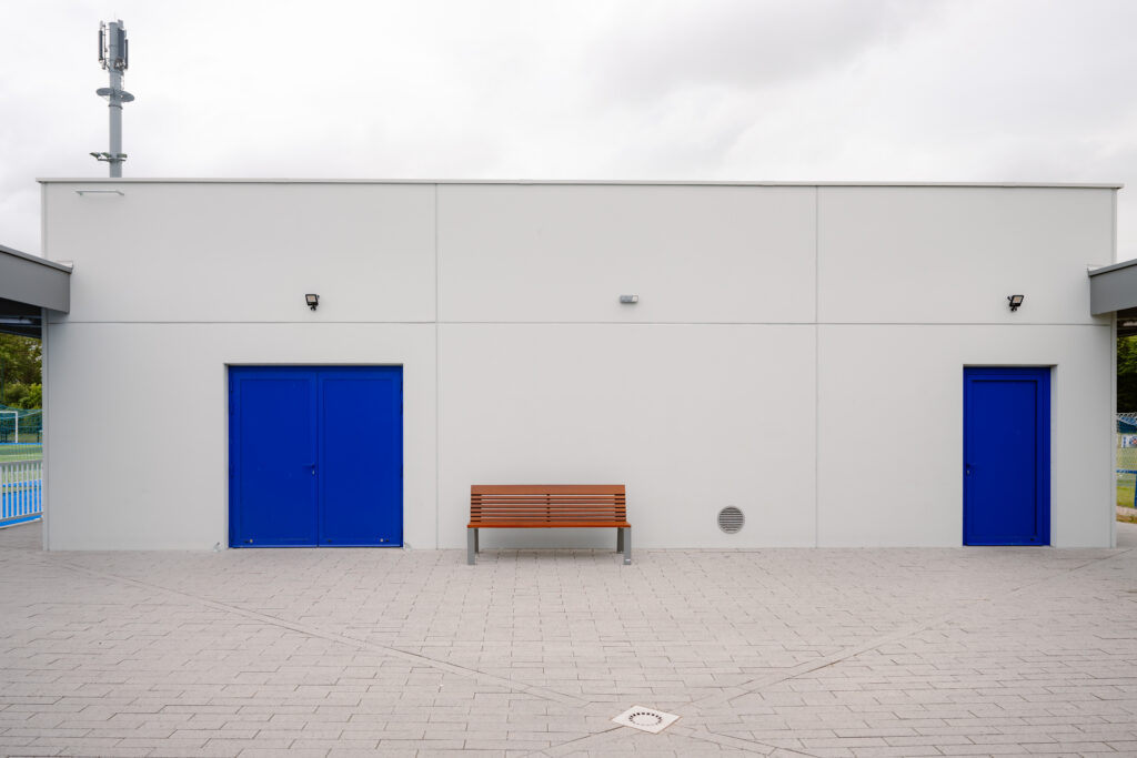 Prefab beton gebouw met blauwe deuren en houten bank in industriebouw